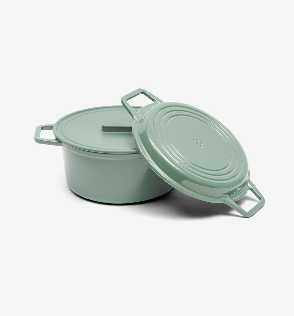Sage green enameled cast iron Dutch oven with lid leaning against pot